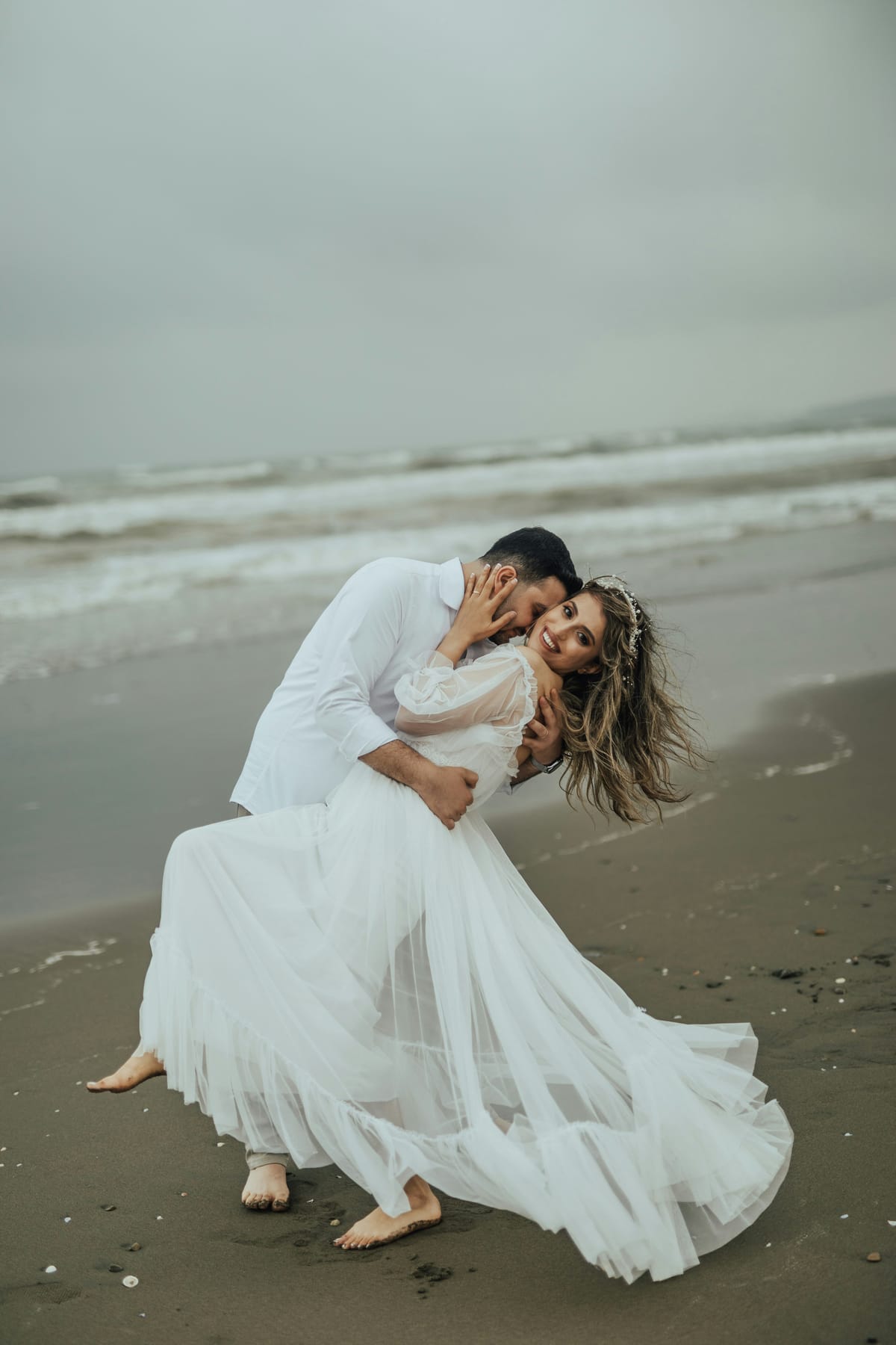 A couple dancing on the shoreline as the waves roll in