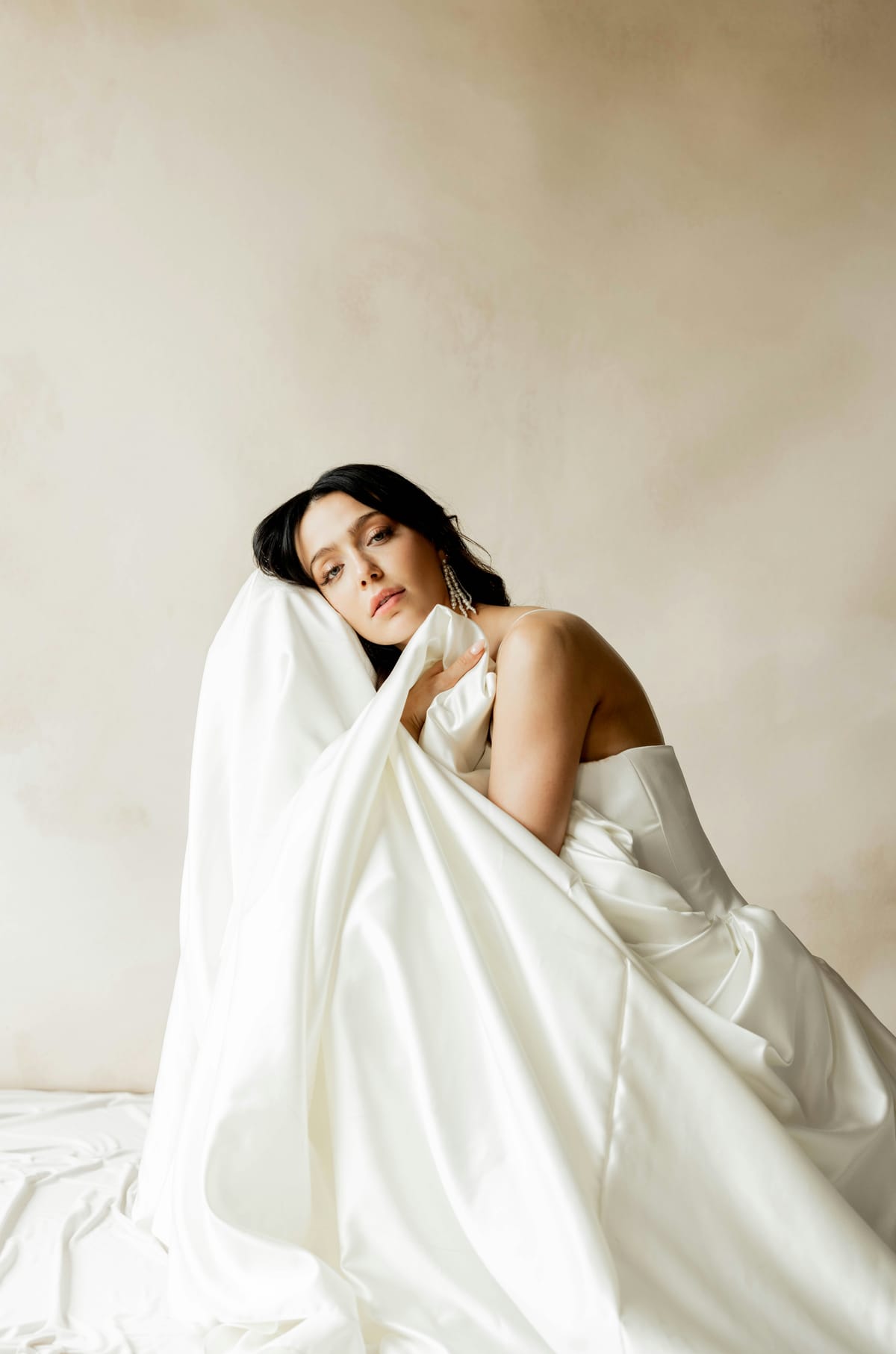 A bride wrapped in the folds of her satin gown