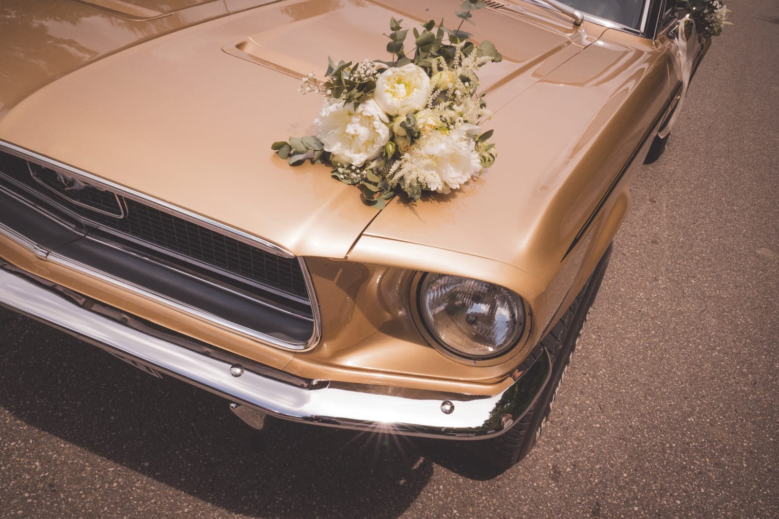 A vintage wedding car with the bouquet resting on its bonnet