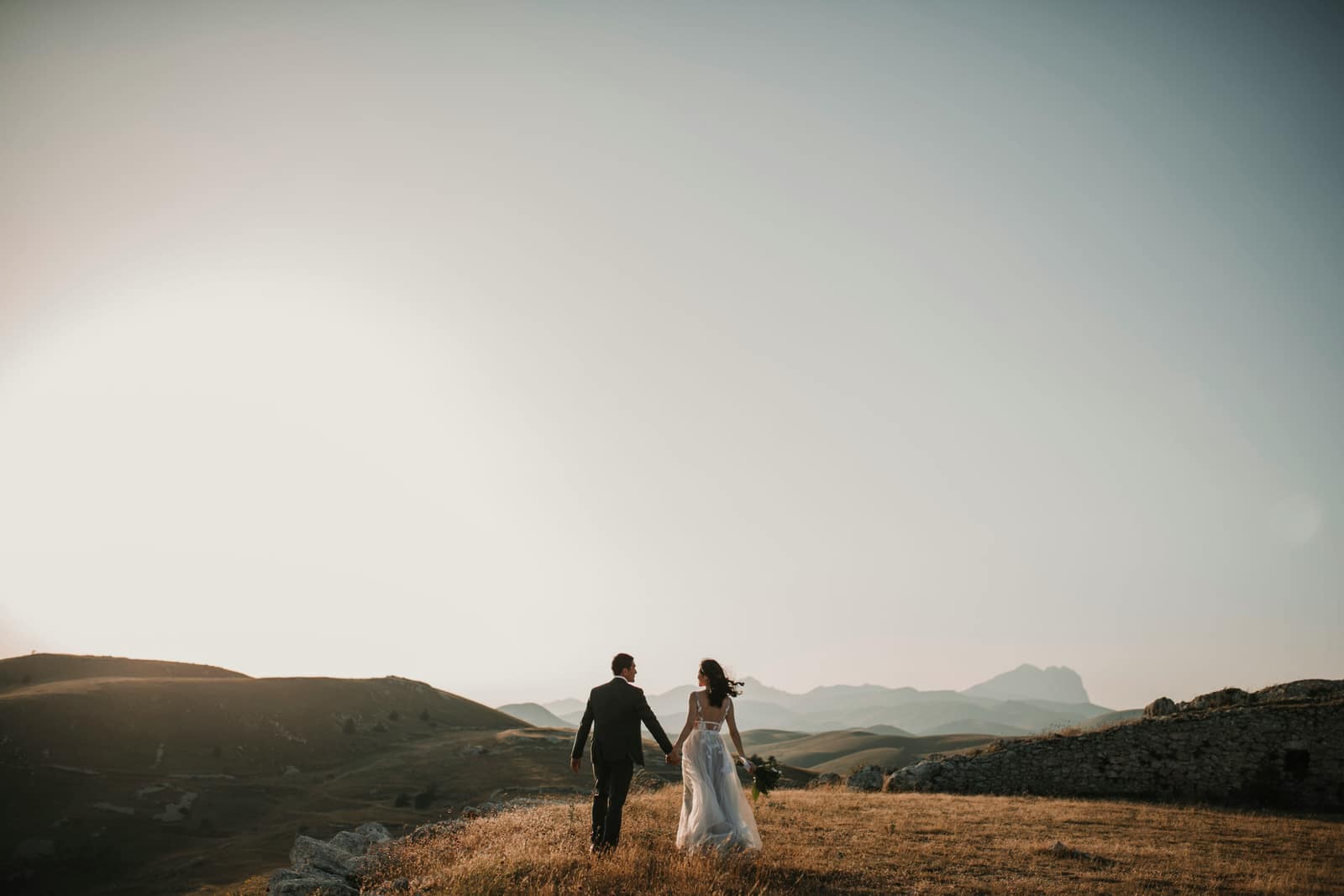 A couple walking the golden estate hills at dusk