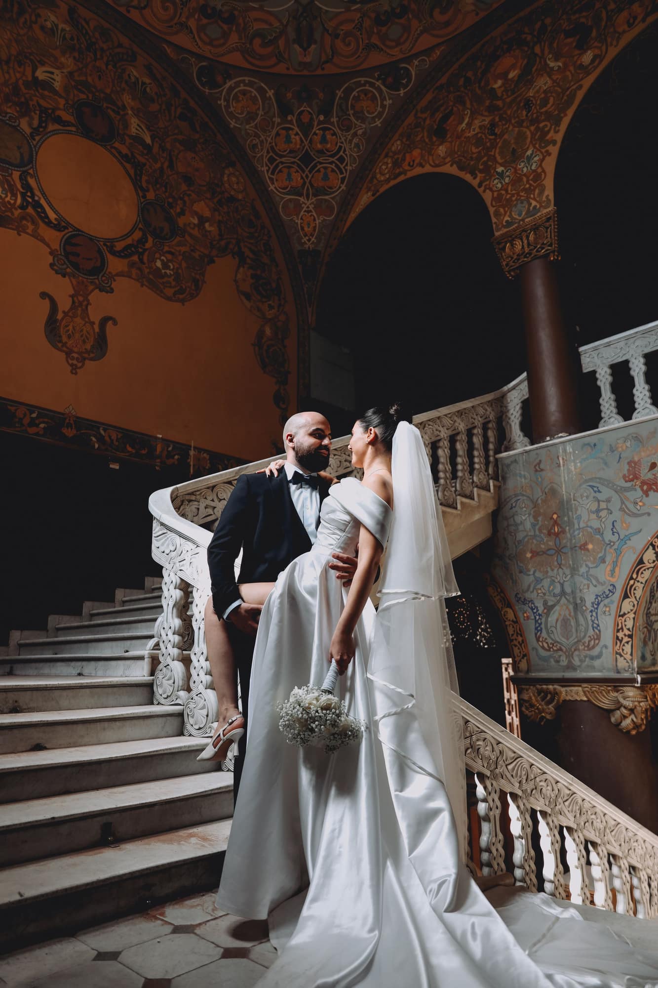 A couple on a grand ornate staircase on their wedding day